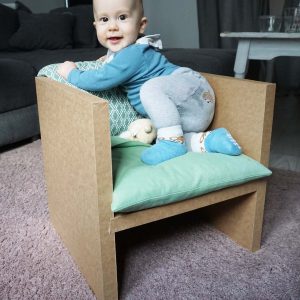 Baby sitzt auf Papphocker